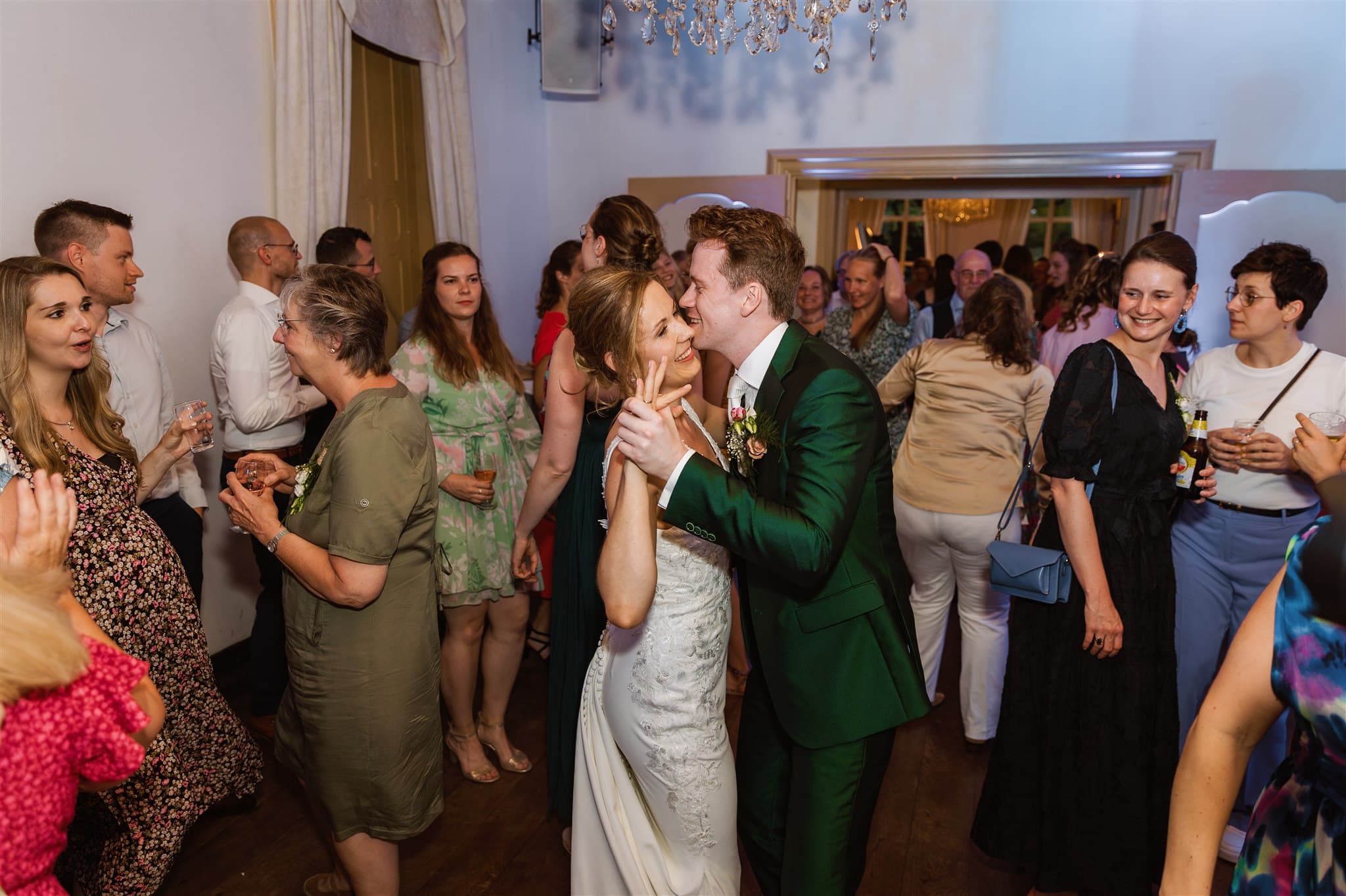 De bruid en bruidegom dansen samen op hun bruiloft bij trouwlocatie Landgoed Lemferdinge, omringd door glimlachende gasten.