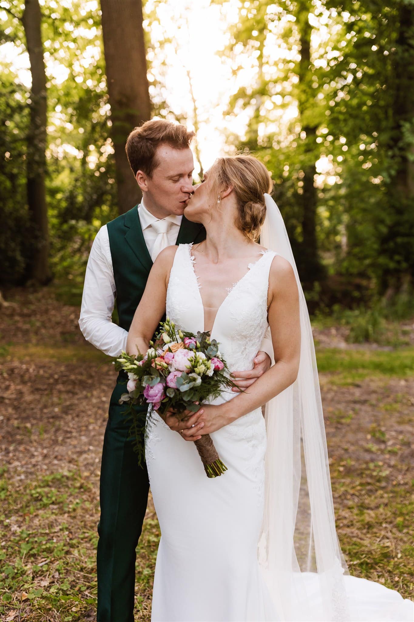 Bruidspaar kust elkaar tijdens golden hour fotoshoot bij Landgoed Lemferdinge.