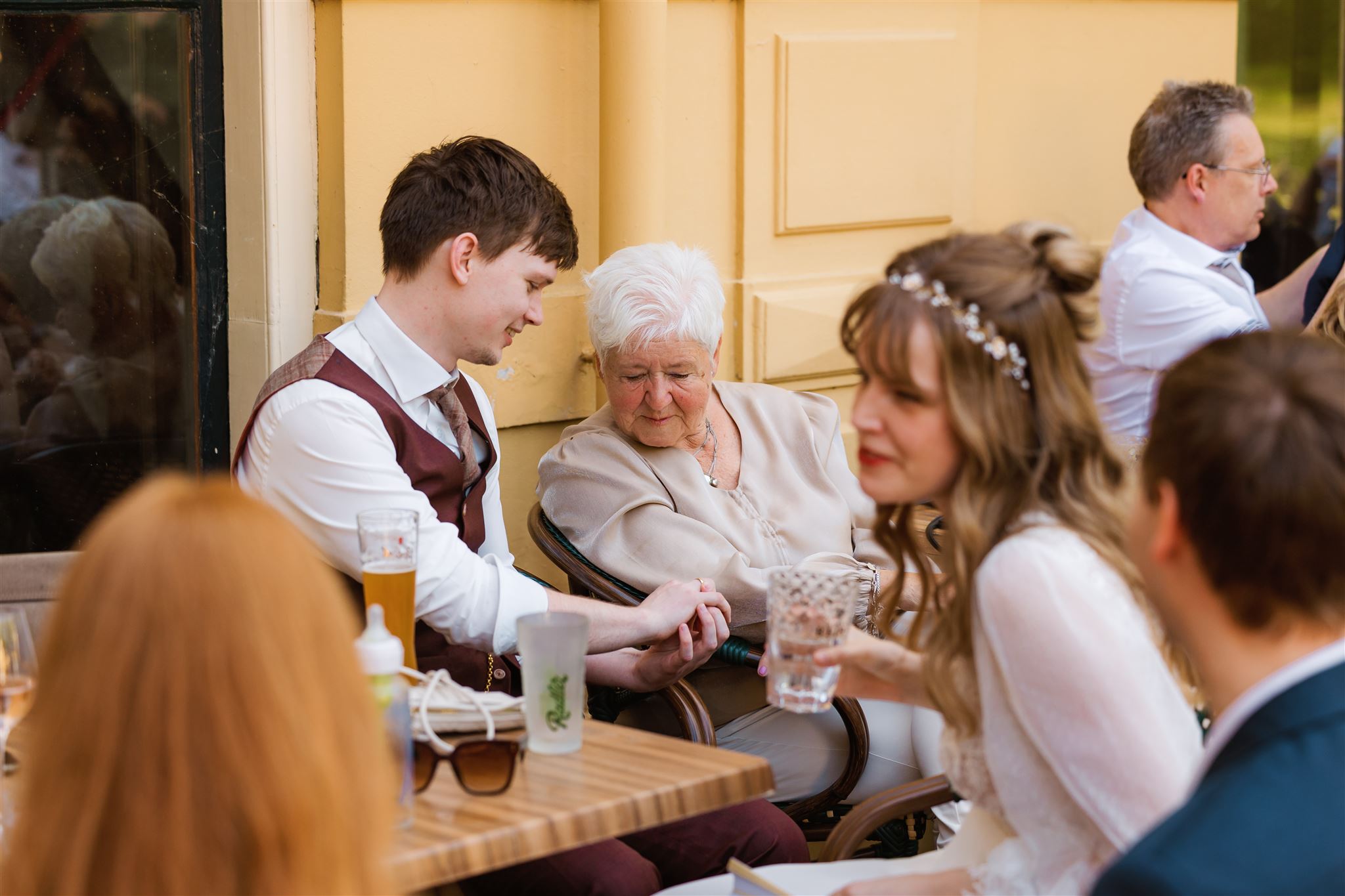 Een bruidegom laat zijn nieuwe trouwring zien aan zijn oma tijdens zijn trouwreceptie.