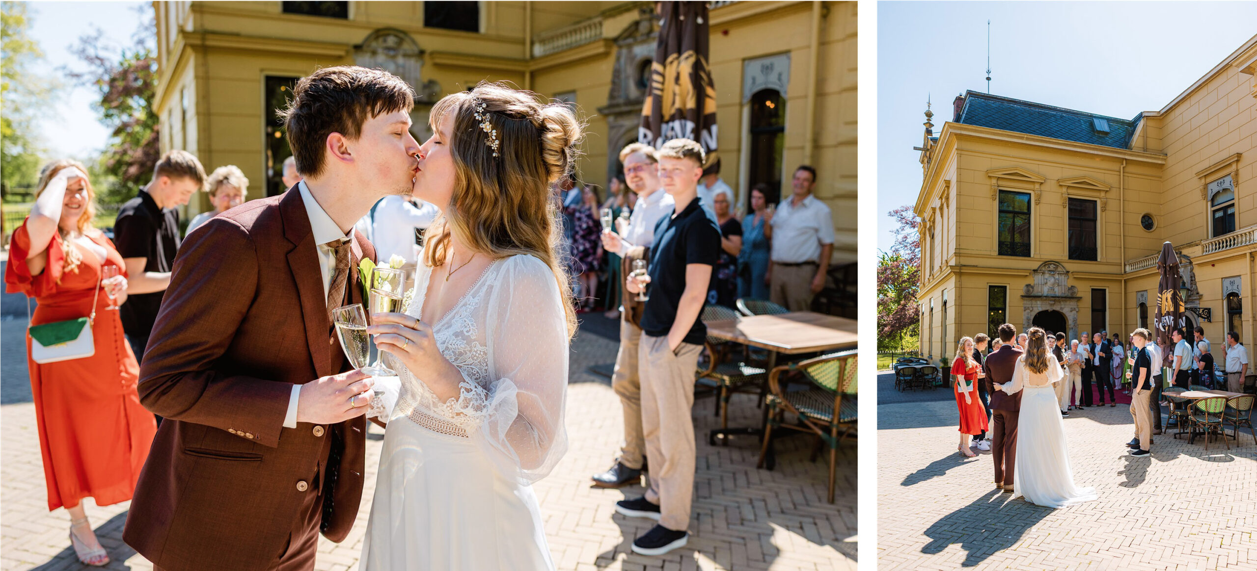 Een bruid en bruidegom kussen elkaar buiten met een drankje in de hand, omringd door bruiloftsgasten op een zonnige locatie.