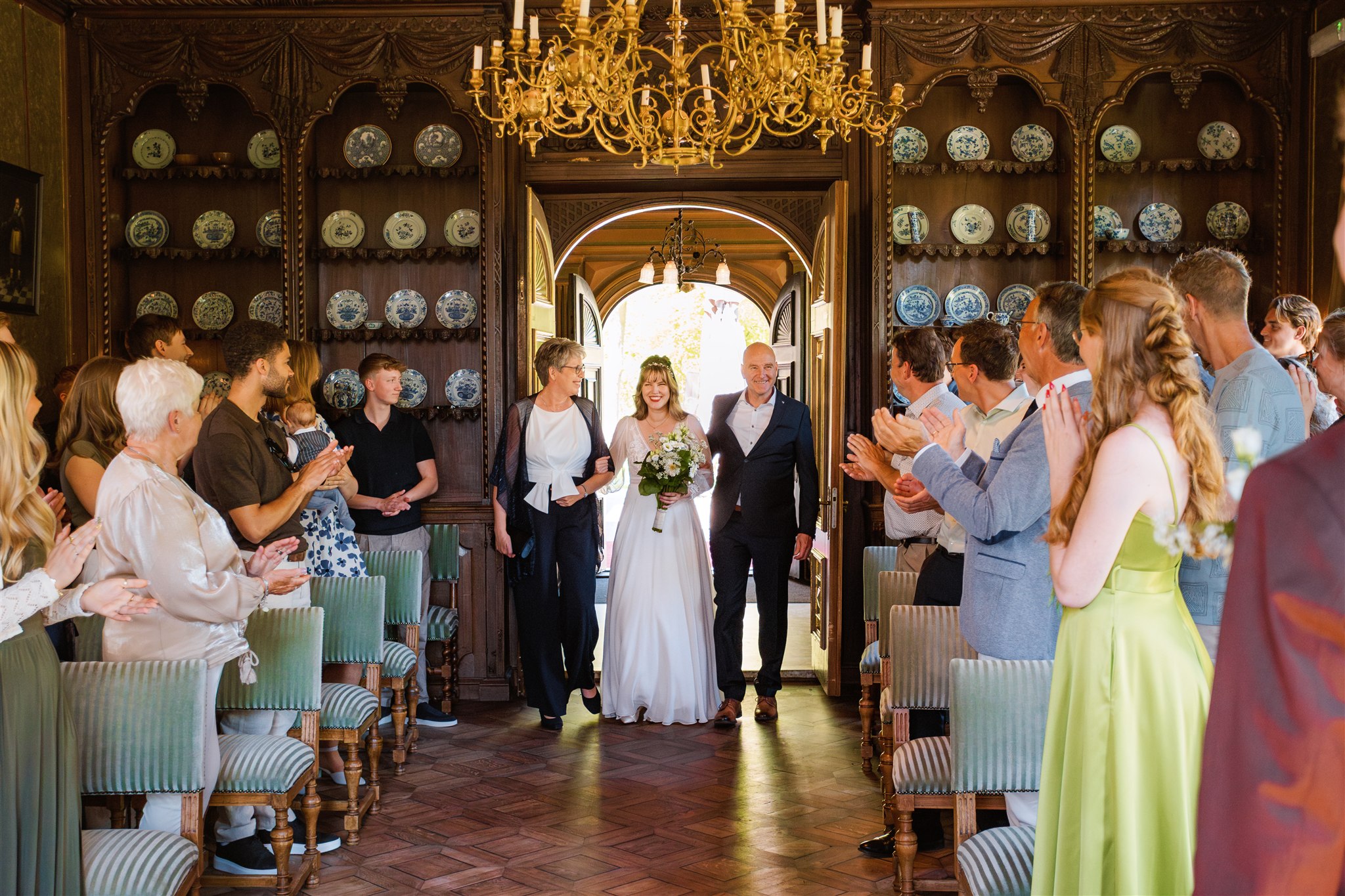 Een bruid komt met haar ouders de Ridderzaal binnen voor haar trouwceremonie bij Borg Nienoord.