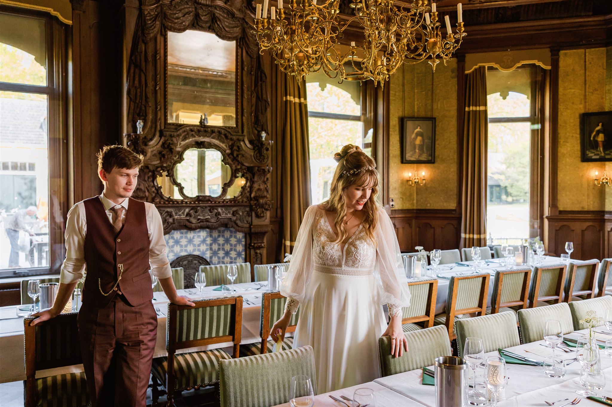 Een bruid en bruidegom bekijken de mooi gedekte tafels voor hun diner.