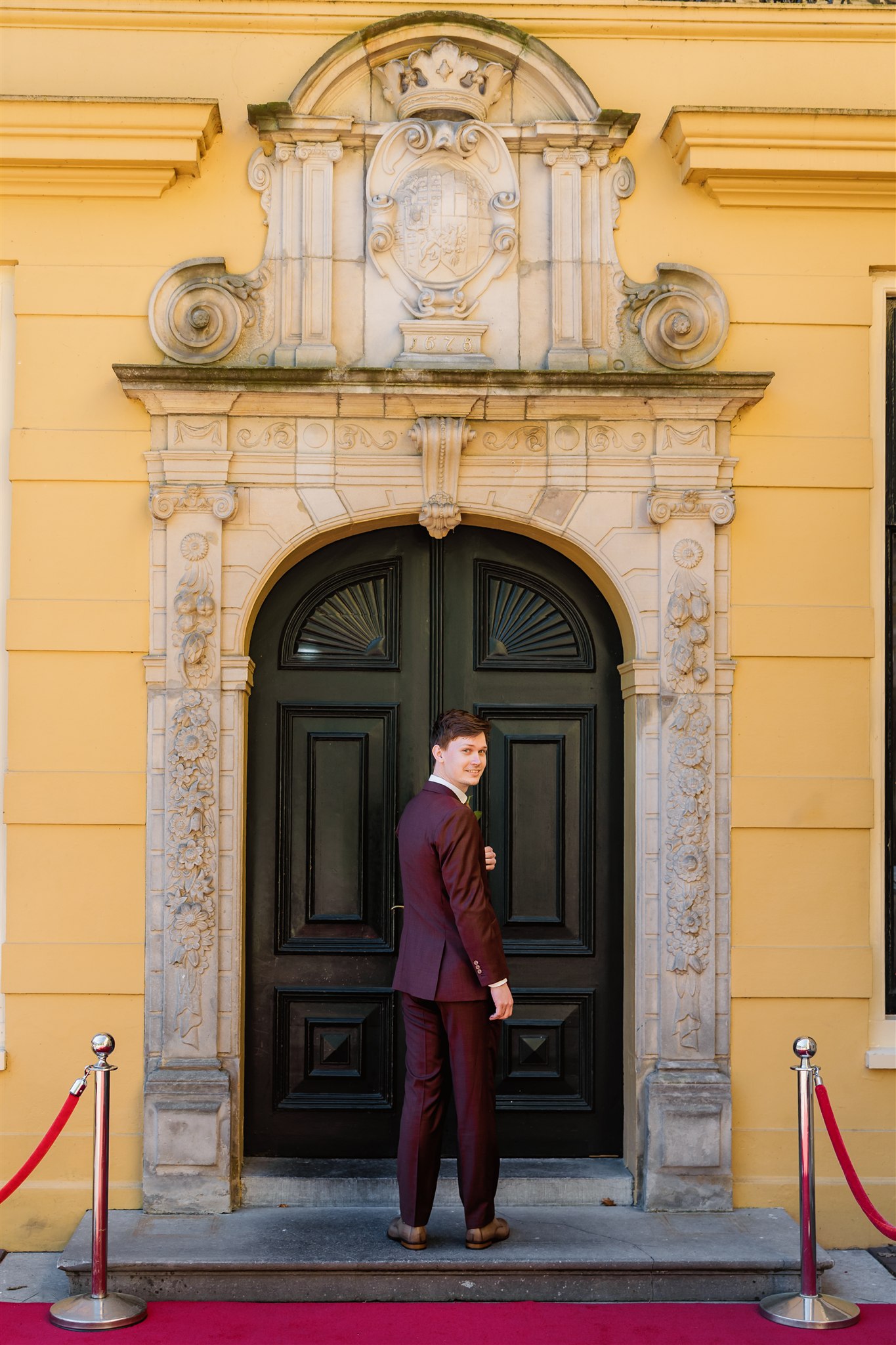 Bruidegom staat voor de monumentale deuren van Borg Nienoord.