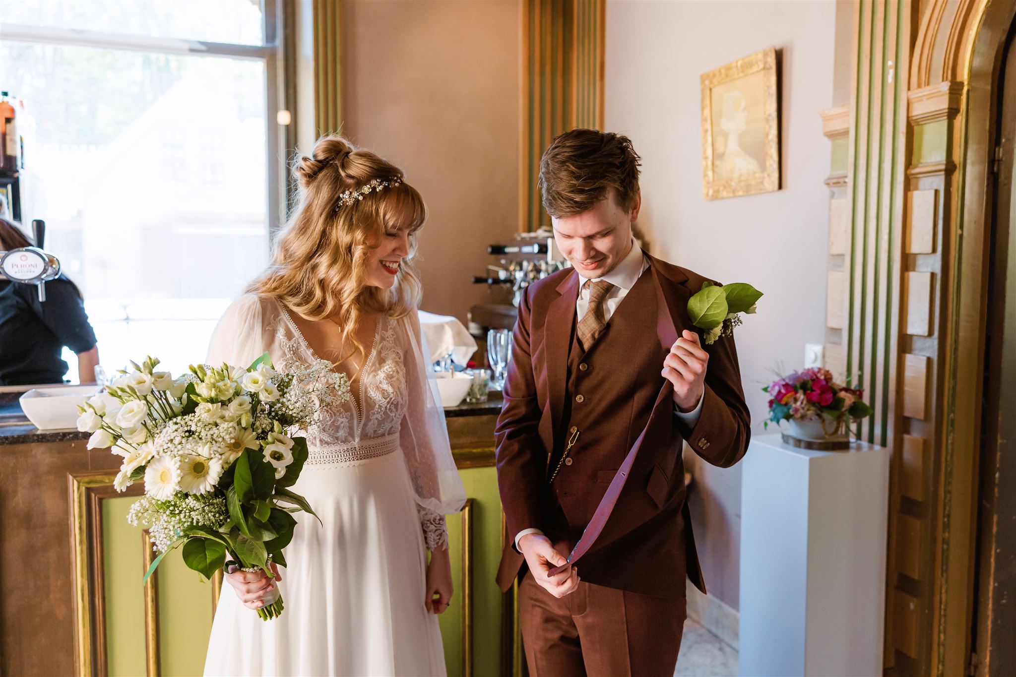 De bruidegom laat de binnenkant van zijn trouwcolbert zien aan zijn bruid.