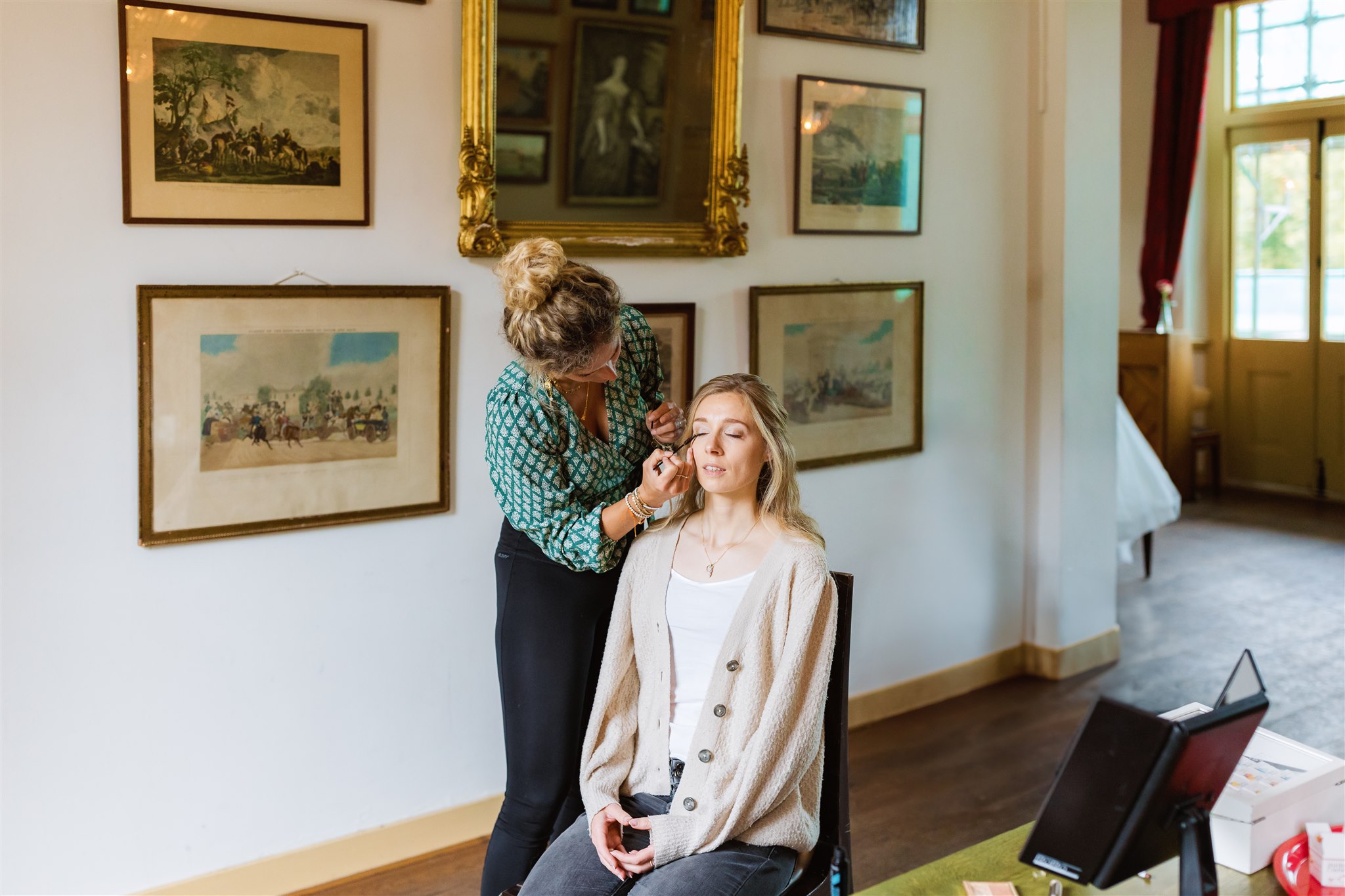 Bruid wordt opgemaakt in de balzaal van Borg Nienoord op haar trouwdag