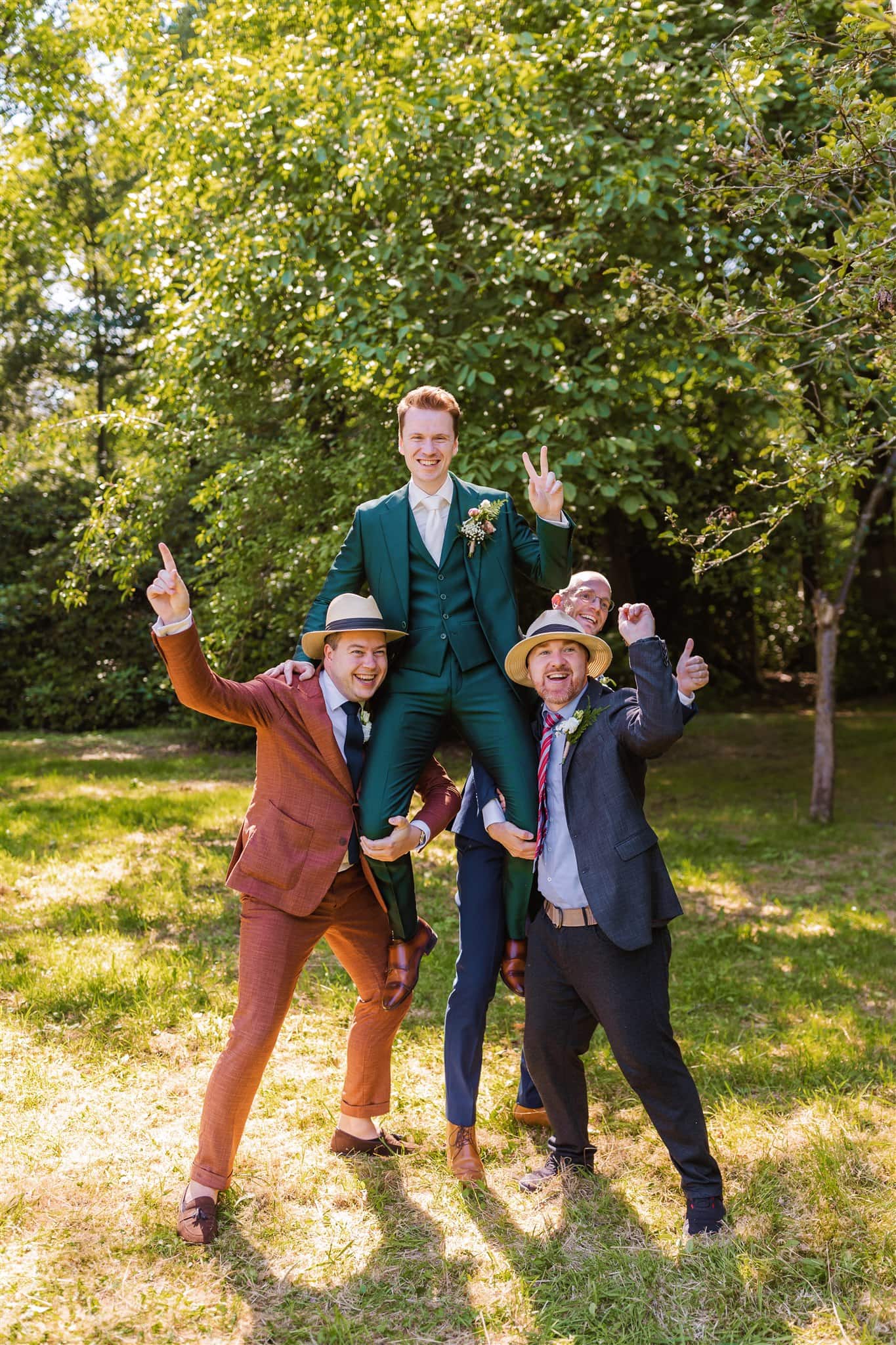De bruidegom wordt voor een groepsfoto op zijn bruiloft opgetild door zijn vrienden.