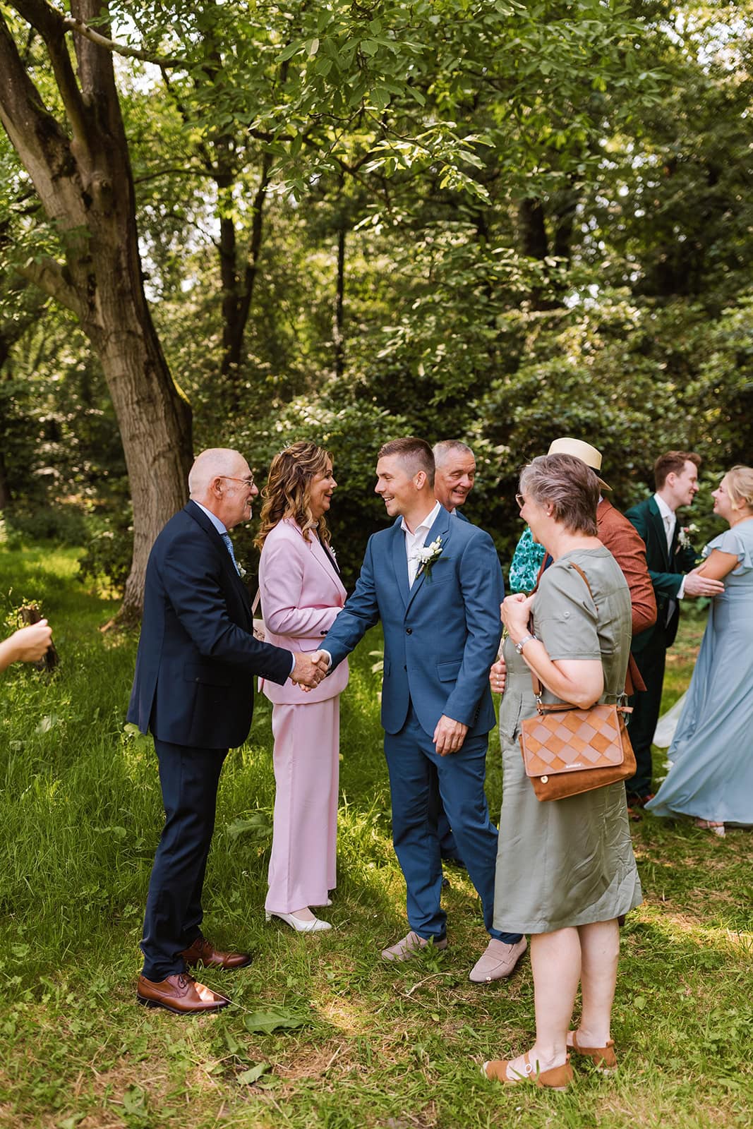 Bruiloftsgasten feliciteren elkaar in de tuin van Landgoed Lemferdinge.