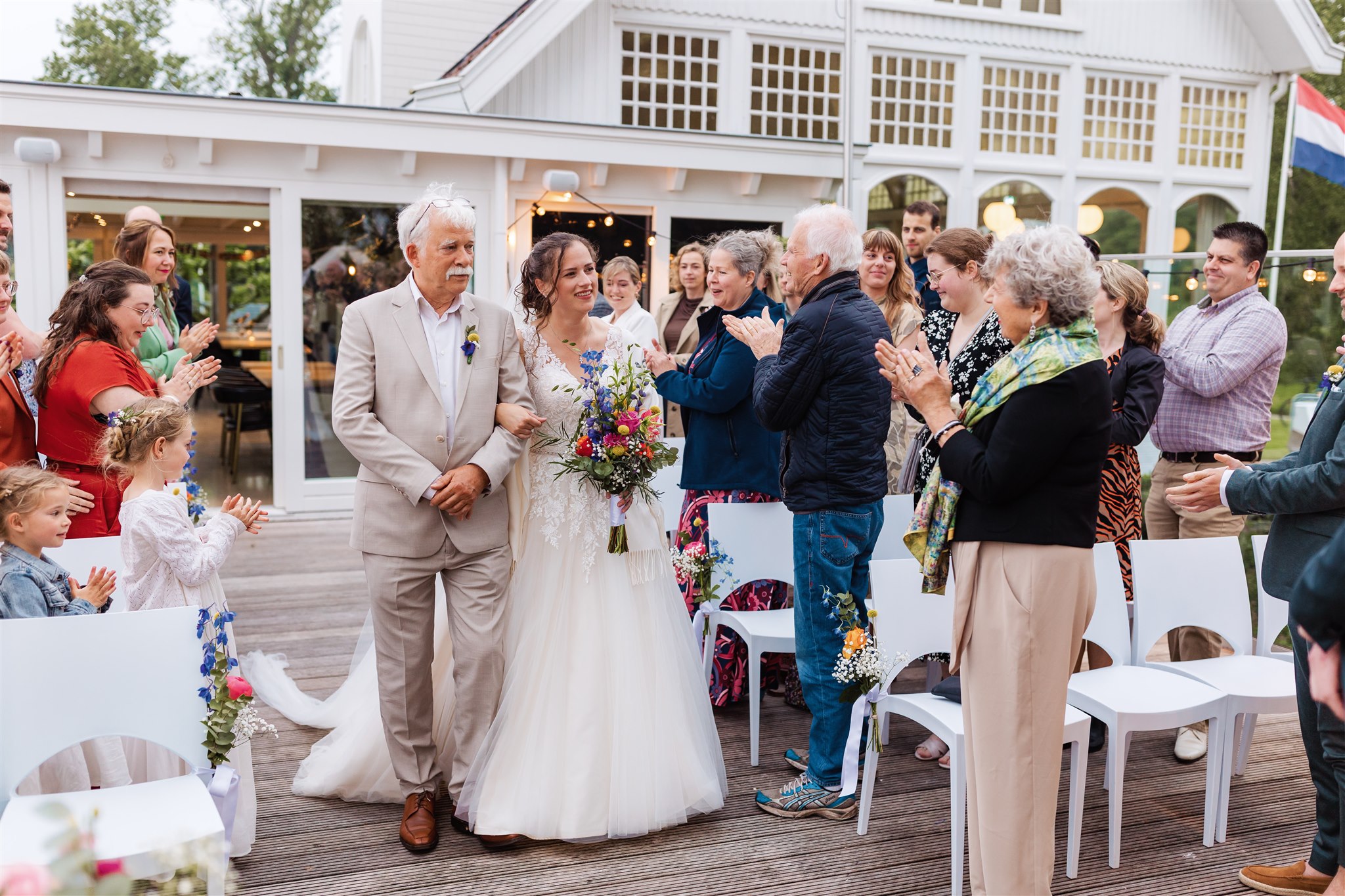 Een bruid loopt met haar vader over het zijterras van de Paalkoepel tijdens de ceremonie.