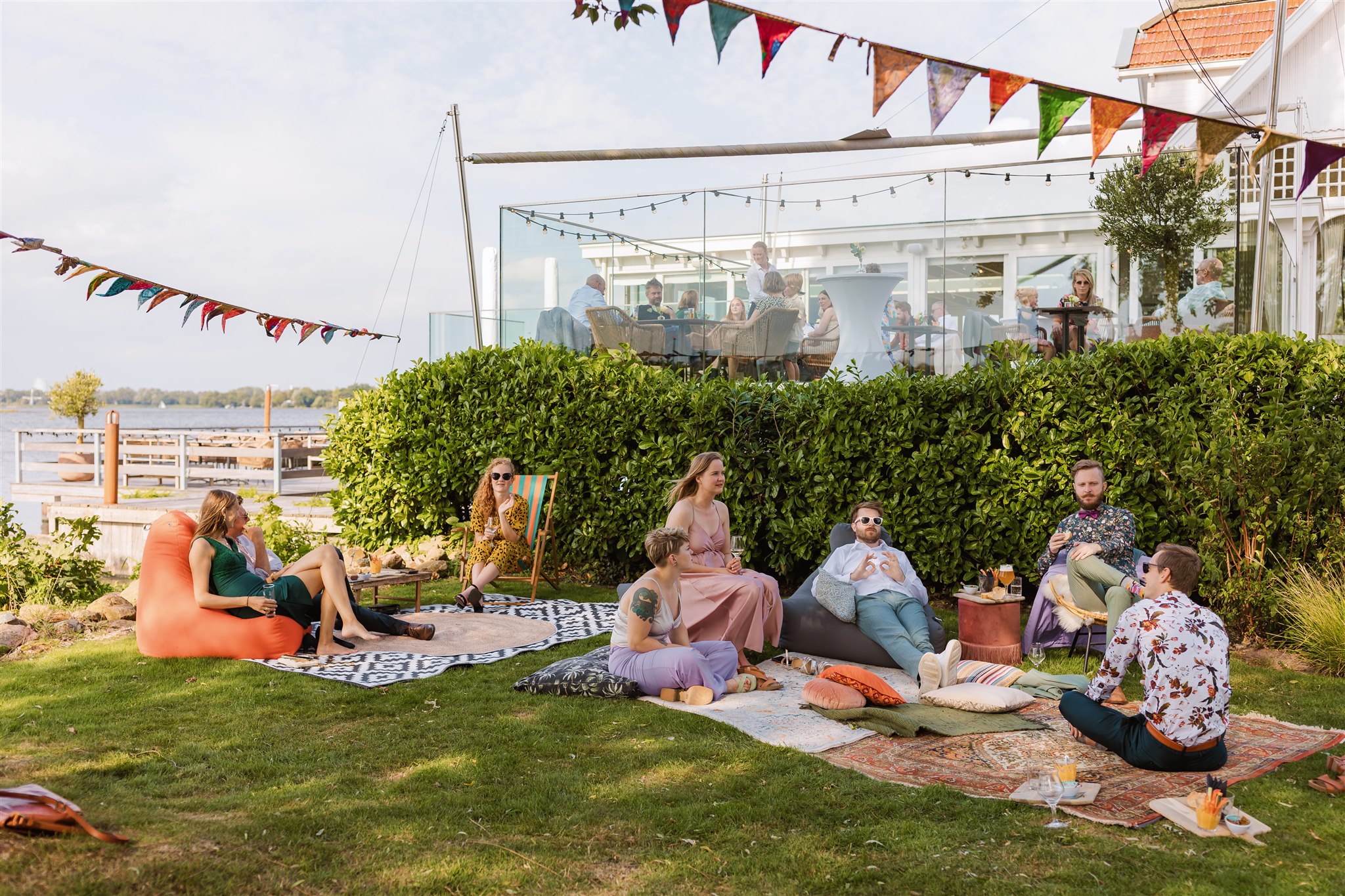 Groep mensen zit op het gras op zitzakken tijdens de receptie van een bruiloft bij de Paalkoepel
