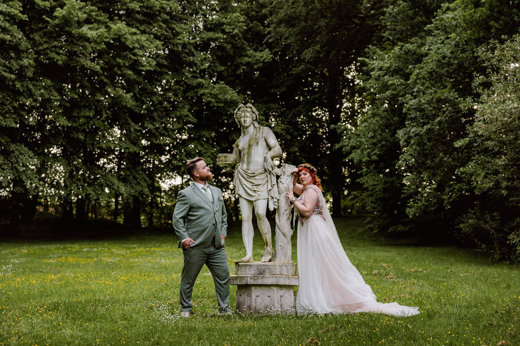 Een bruid en bruidegom poseren naast een stenen standbeeld in Park Vijversburg in Tytsjerk.